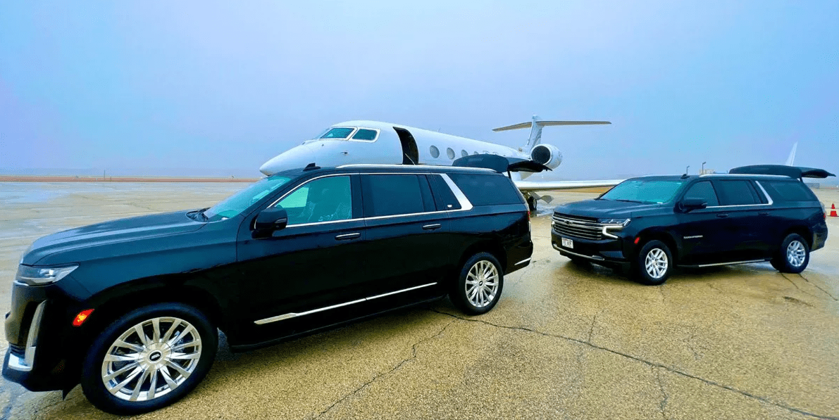 A photo showing two SUVs parked near an airplane