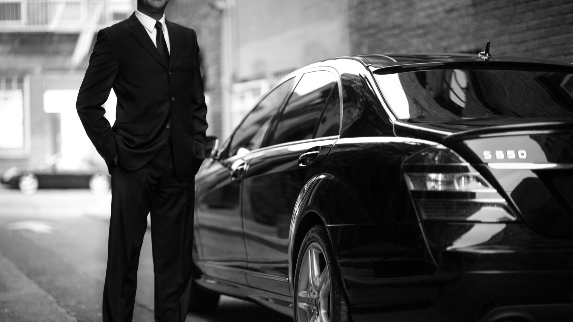 A man in a suit standing next to a car